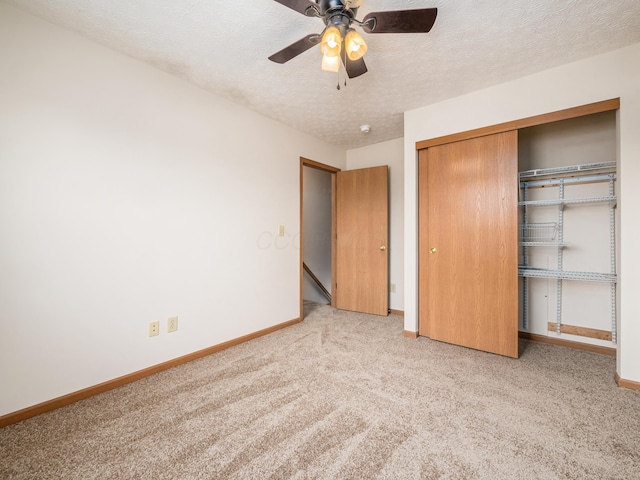 unfurnished bedroom with ceiling fan, a textured ceiling, a closet, and light carpet