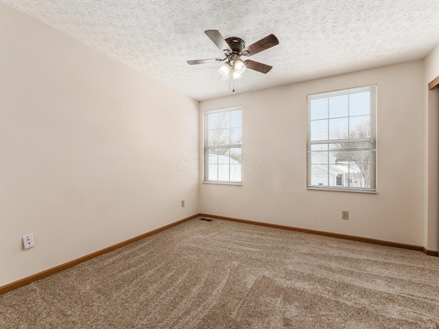 spare room featuring a textured ceiling, ceiling fan, a healthy amount of sunlight, and carpet floors