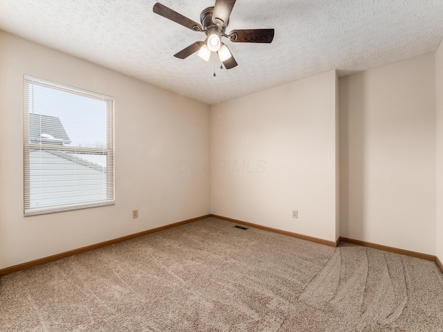 spare room featuring a textured ceiling, ceiling fan, and carpet