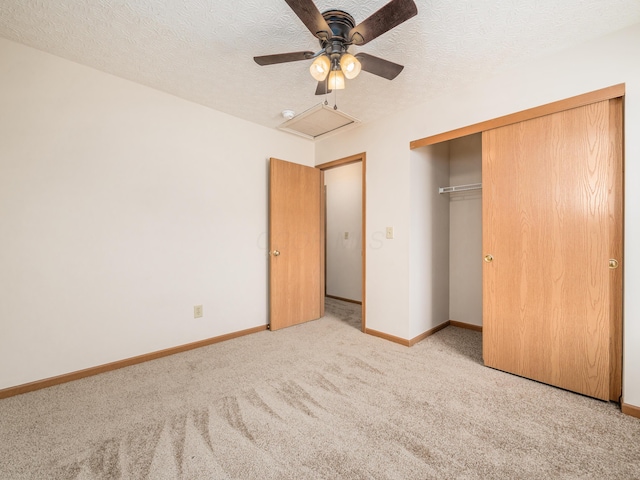 unfurnished bedroom with light carpet, ceiling fan, a closet, and a textured ceiling