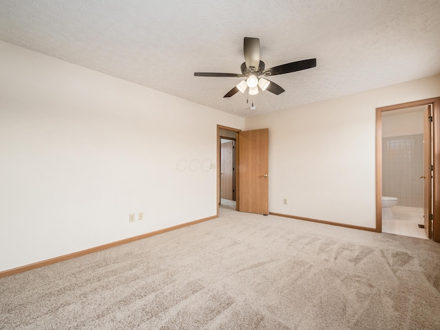 unfurnished bedroom featuring ceiling fan, carpet, connected bathroom, and a textured ceiling