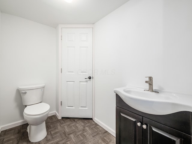 bathroom with toilet, vanity, and parquet floors