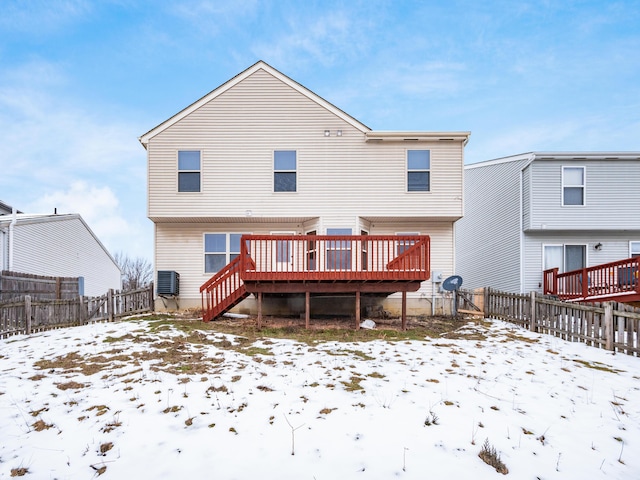 snow covered back of property with a deck and central AC