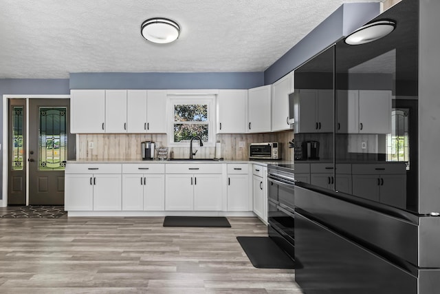 kitchen with white cabinets, double oven range, decorative backsplash, and sink