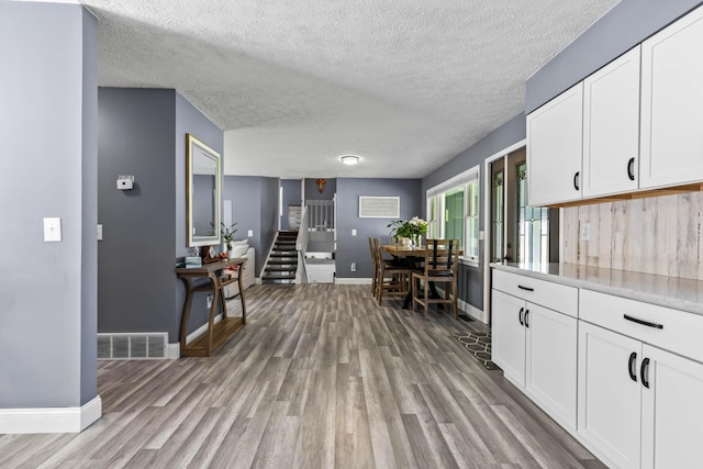 kitchen with light hardwood / wood-style floors, white cabinetry, and a textured ceiling