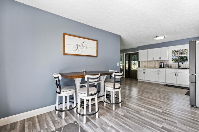 dining room with sink, a textured ceiling, and hardwood / wood-style floors