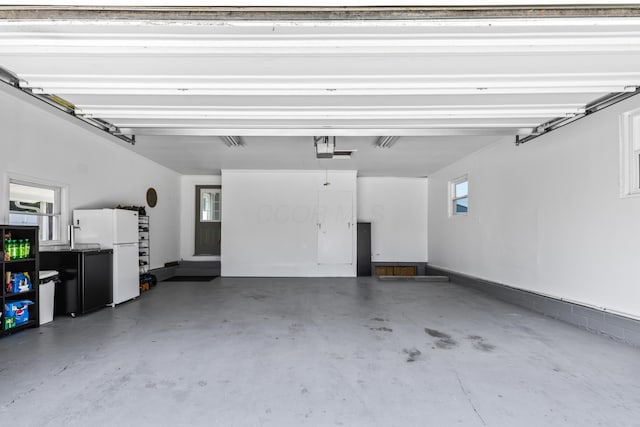 garage featuring white refrigerator and a garage door opener