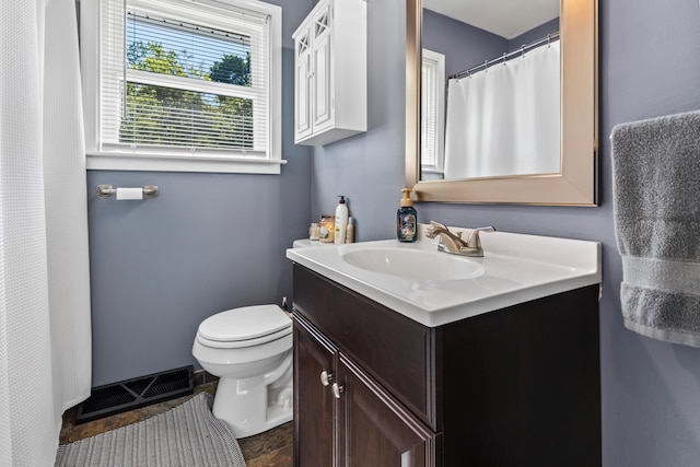 bathroom featuring toilet, vanity, and curtained shower