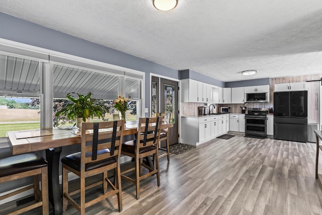 kitchen featuring appliances with stainless steel finishes, plenty of natural light, a textured ceiling, white cabinetry, and tasteful backsplash