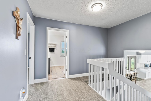 corridor with a textured ceiling and light colored carpet