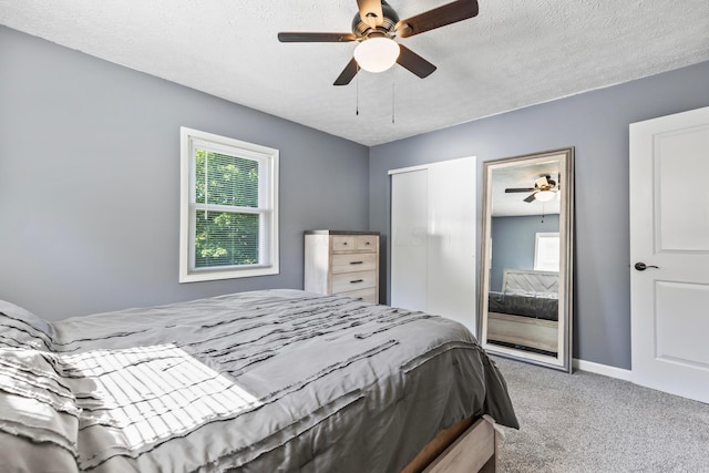 bedroom with ceiling fan, multiple windows, carpet flooring, and a textured ceiling