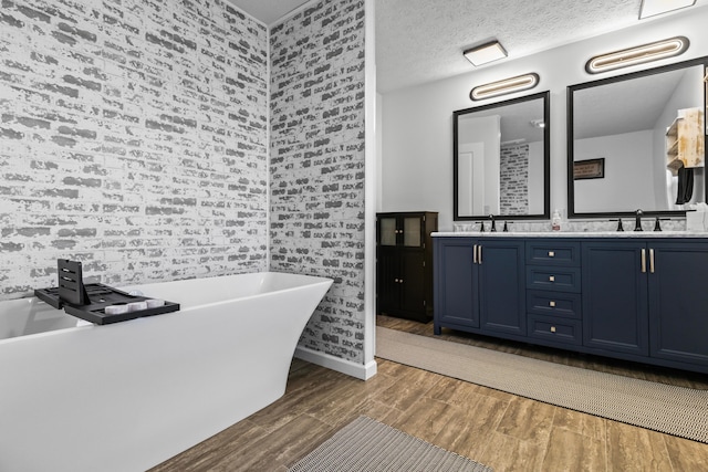 bathroom with a bath, a textured ceiling, vanity, and wood-type flooring