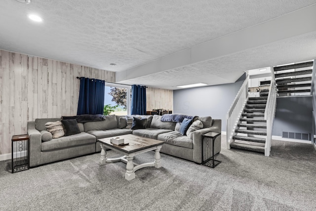 living room with wood walls, a textured ceiling, and carpet floors