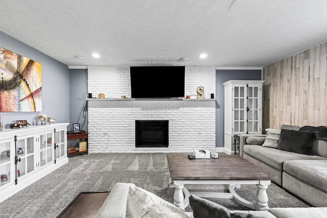 carpeted living room featuring a textured ceiling, wood walls, and a fireplace