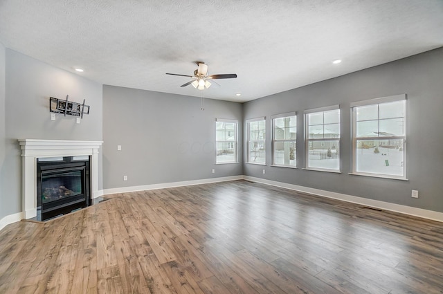 unfurnished living room with wood-type flooring, a textured ceiling, and ceiling fan