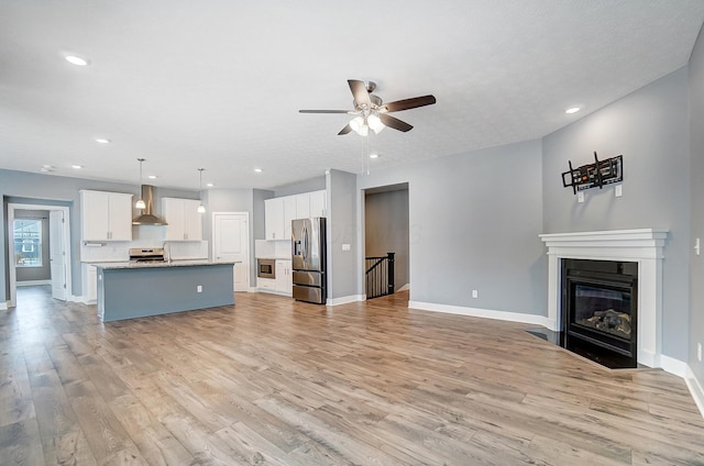 unfurnished living room featuring light hardwood / wood-style floors, ceiling fan, and a textured ceiling