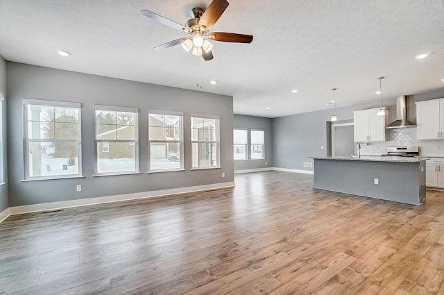 unfurnished living room with sink, wood-type flooring, a textured ceiling, and ceiling fan