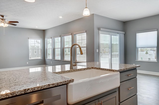 kitchen featuring sink, pendant lighting, gray cabinets, and light stone countertops