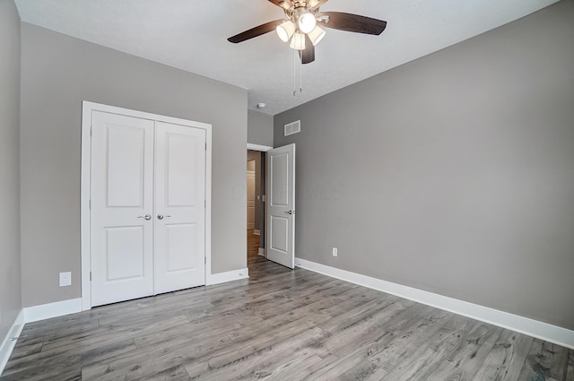 unfurnished bedroom featuring ceiling fan, light hardwood / wood-style floors, and a closet