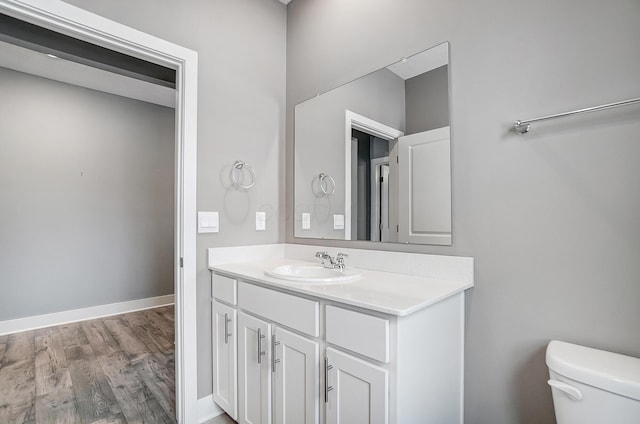 bathroom with toilet, wood-type flooring, and vanity