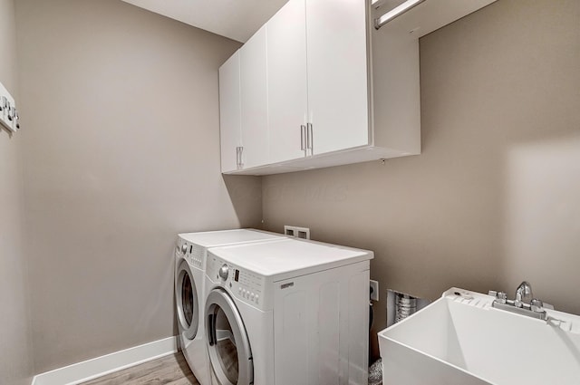 laundry area featuring sink, separate washer and dryer, cabinets, and light hardwood / wood-style flooring