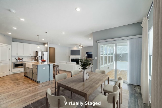 dining area featuring light wood-type flooring, ceiling fan, and sink