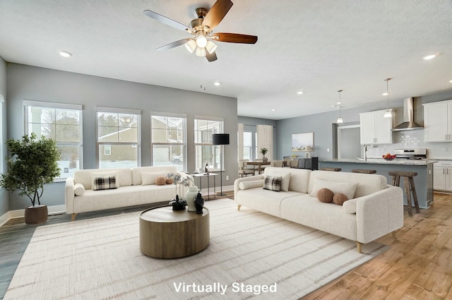 living room featuring light wood-type flooring, ceiling fan, a textured ceiling, and sink