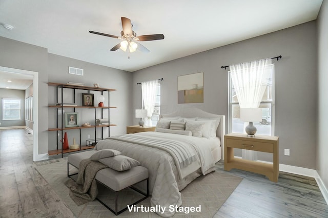 bedroom featuring ceiling fan, light hardwood / wood-style floors, and multiple windows