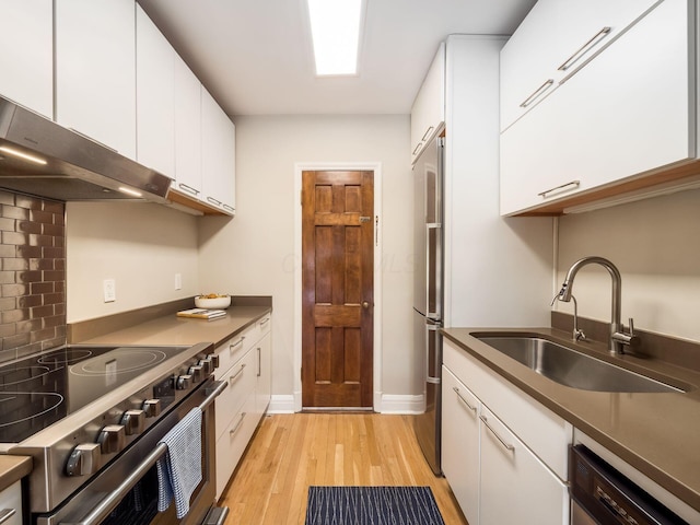 kitchen with light wood-type flooring, appliances with stainless steel finishes, white cabinets, and sink