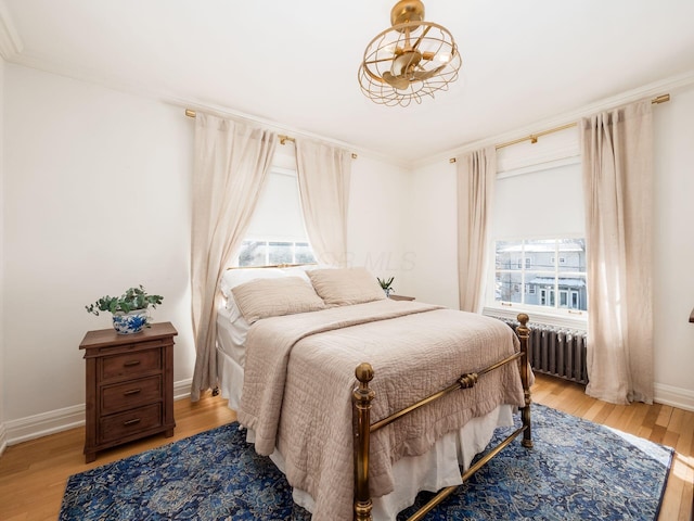 bedroom with radiator heating unit, ornamental molding, and light hardwood / wood-style flooring