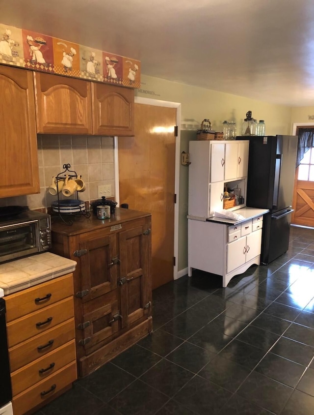 kitchen featuring black refrigerator and tasteful backsplash