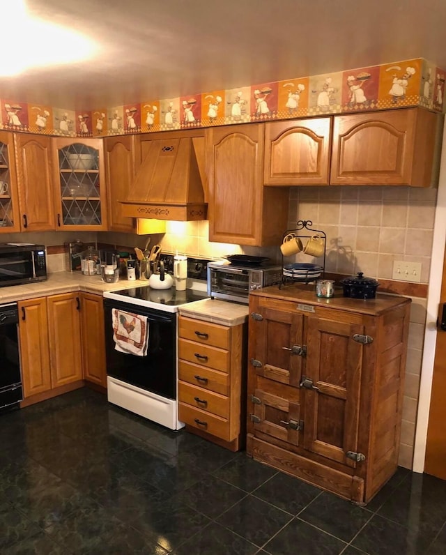 kitchen with black appliances, decorative backsplash, dark tile patterned floors, and custom range hood