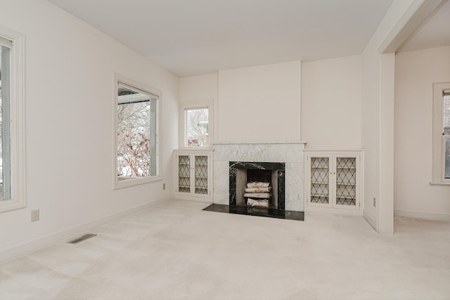 unfurnished living room with light carpet and a fireplace