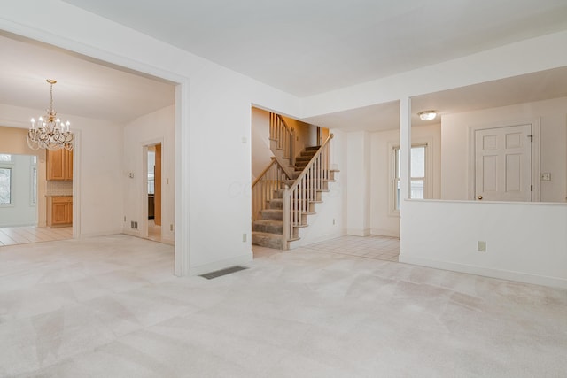 carpeted spare room featuring an inviting chandelier