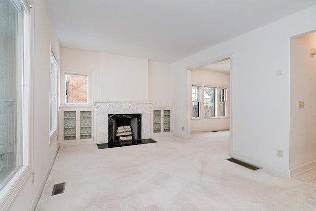 unfurnished living room featuring a premium fireplace and light colored carpet