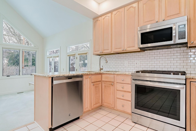 kitchen with appliances with stainless steel finishes, light brown cabinetry, backsplash, kitchen peninsula, and light stone counters