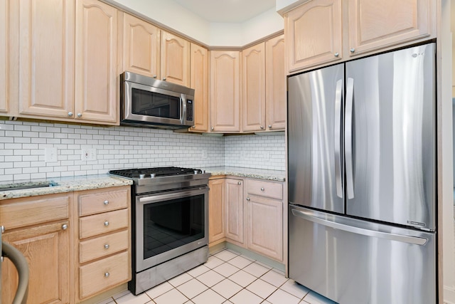 kitchen featuring appliances with stainless steel finishes, light brown cabinetry, tasteful backsplash, and light stone countertops