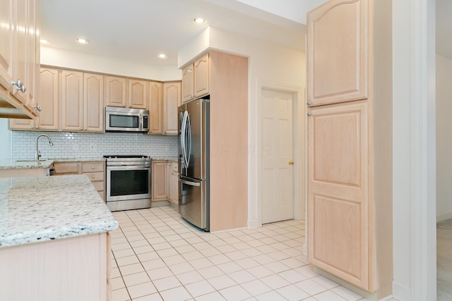 kitchen with decorative backsplash, light brown cabinetry, and stainless steel appliances