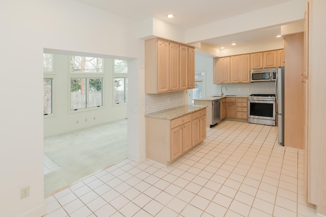 kitchen featuring tasteful backsplash, appliances with stainless steel finishes, light stone countertops, light carpet, and light brown cabinetry