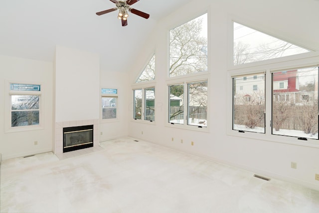 unfurnished living room with light carpet, ceiling fan, a fireplace, and high vaulted ceiling