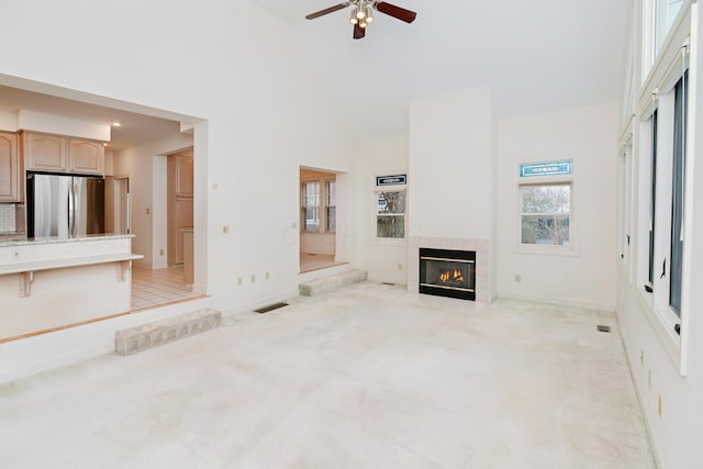 unfurnished living room featuring light carpet, ceiling fan, and a fireplace