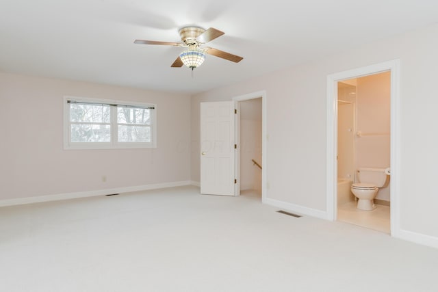 unfurnished bedroom with ensuite bath, a spacious closet, ceiling fan, and carpet