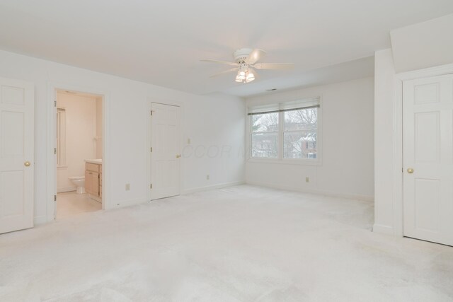 unfurnished bedroom with ceiling fan, light colored carpet, and ensuite bath