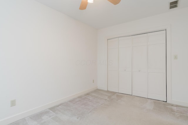 unfurnished bedroom with ceiling fan, a closet, and light carpet