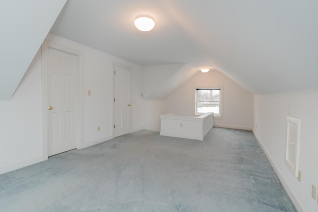 additional living space with light colored carpet and vaulted ceiling