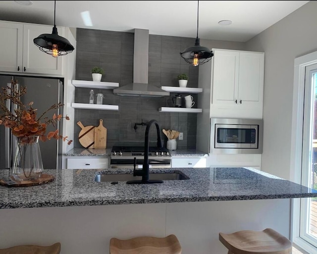 kitchen with stainless steel appliances, wall chimney range hood, and a breakfast bar area