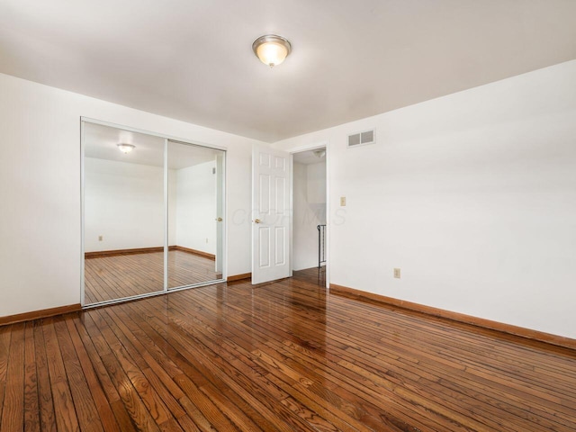 unfurnished bedroom featuring a closet and dark wood-type flooring