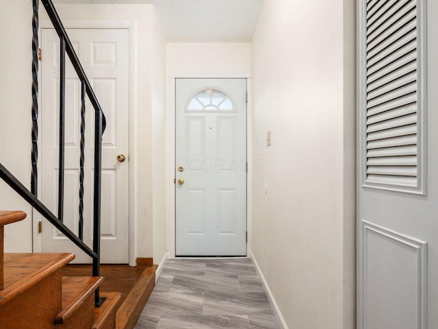 foyer entrance with light wood-type flooring and a textured ceiling