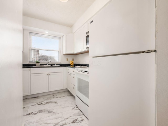 kitchen featuring white appliances, white cabinetry, and sink