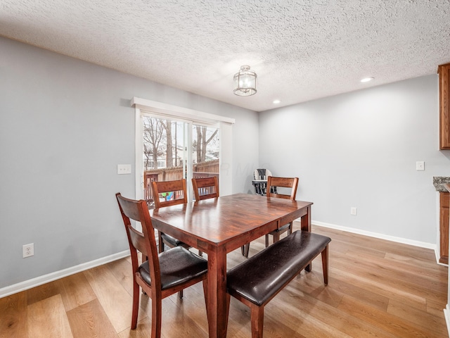 dining area featuring a textured ceiling and light hardwood / wood-style flooring